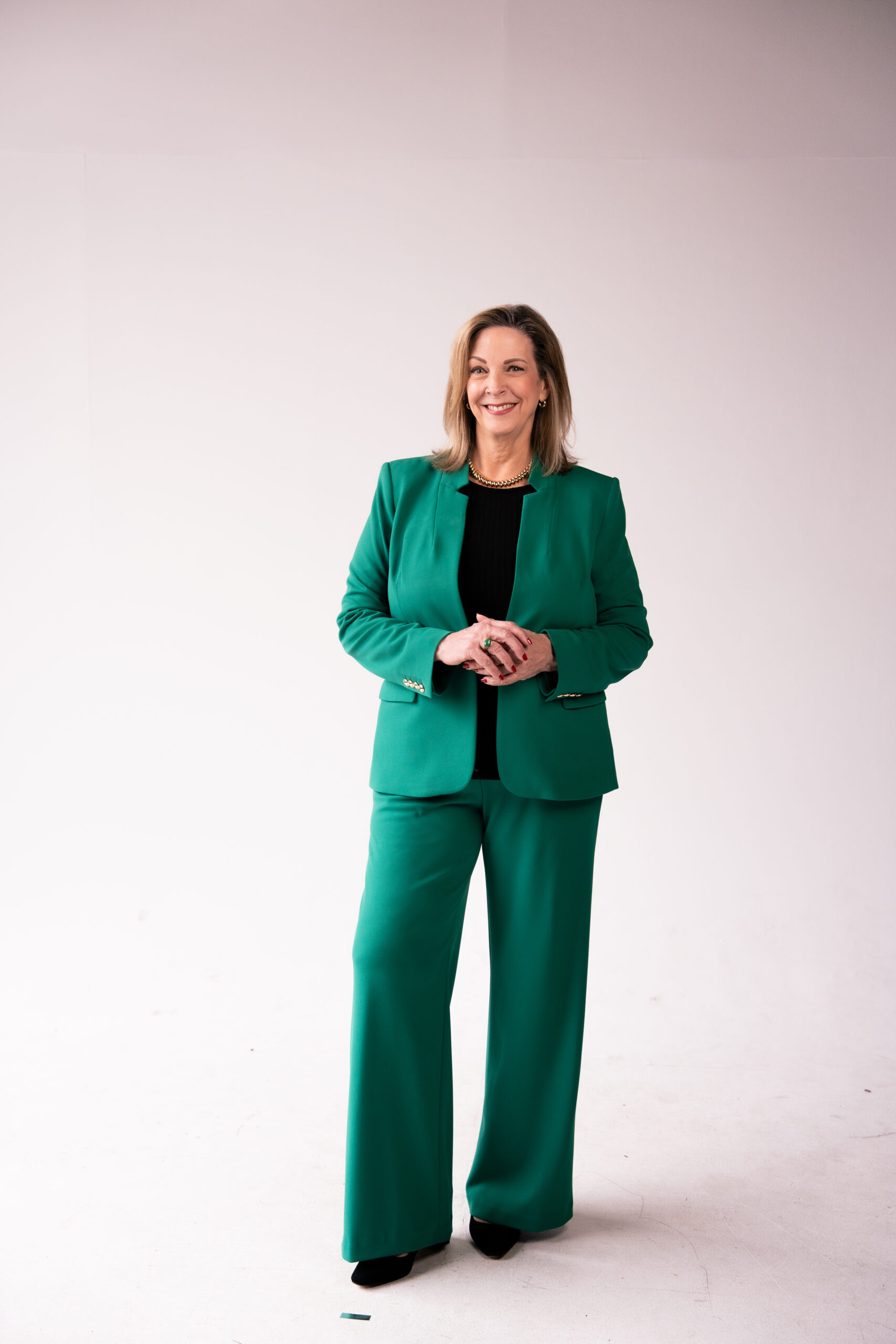 Marcia Miller standing in a photo studio in a green pantsuit